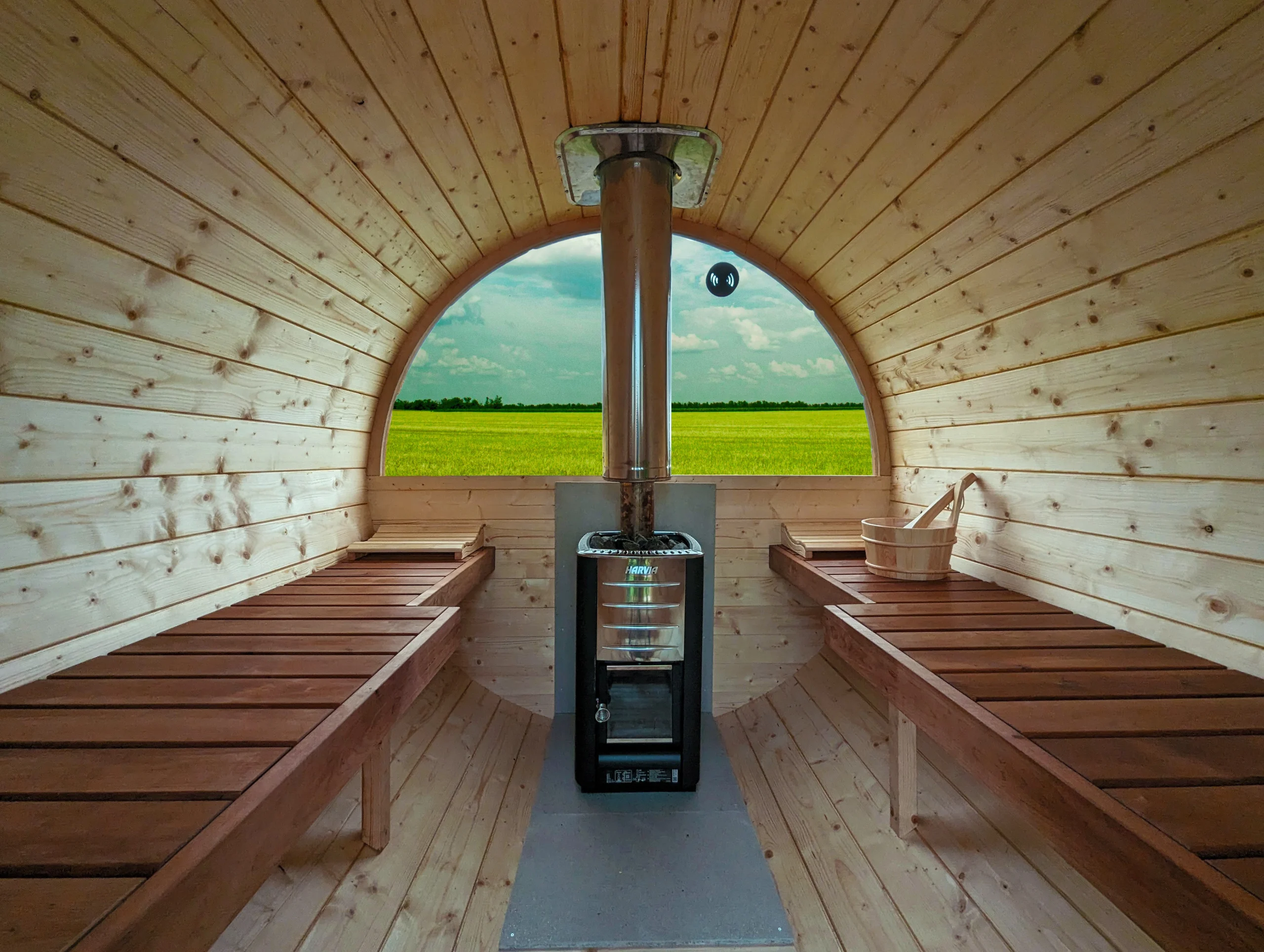 Innenansicht einer Fasssauna mit Holzofen und Sitzbänken
